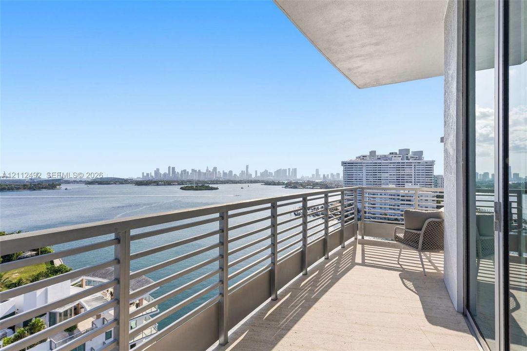 Covered balcony featuring natural stone flooring and horizontal metal railings