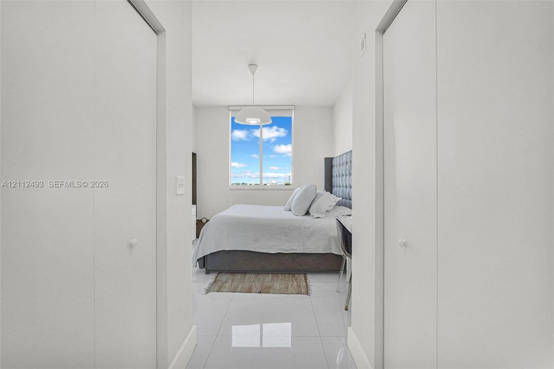 Neutral interior featuring large-format tile flooring, dual floor-to-ceiling closets, and an oversized window providing natural light