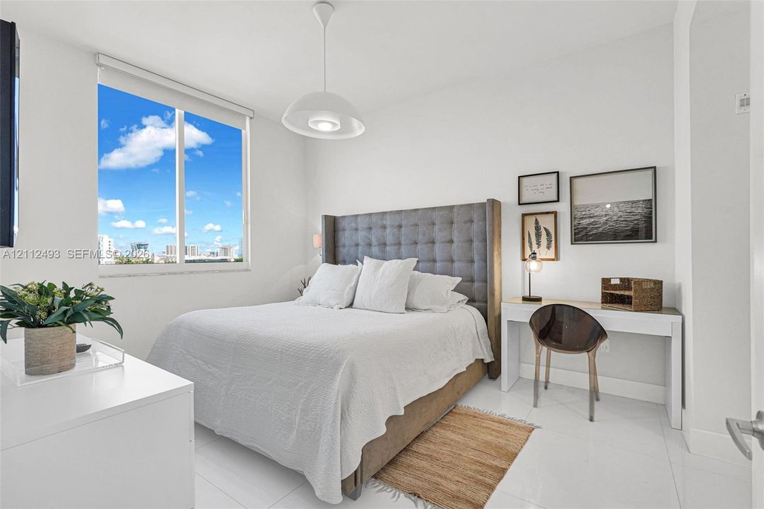 Bright room featuring large-format tile flooring, expansive window, and a central pendant light fixture