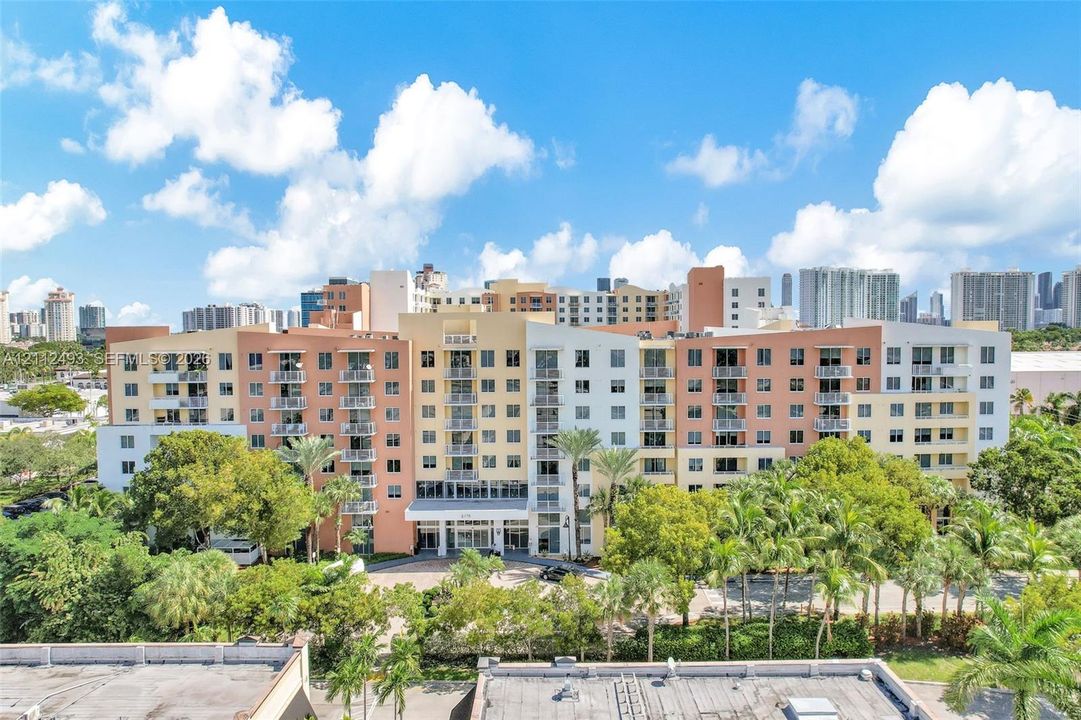 Multi-story residential complex featuring private balconies, expansive glass fenestration, and mature perimeter landscaping