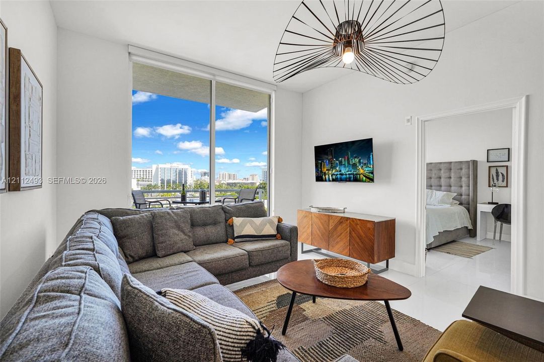 Floor-to-ceiling windows, sculptural pendant lighting, polished tile flooring, and a private balcony