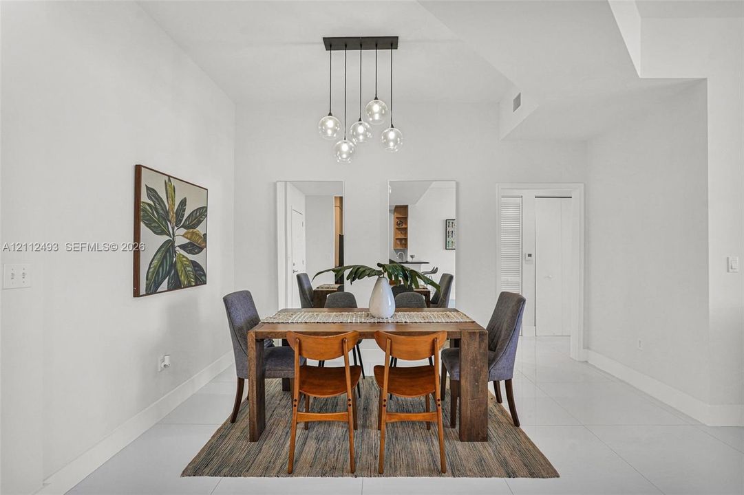 Dining space featuring high-gloss tile flooring, smooth ceiling finishes, and a contemporary multi-light glass pendant fixture
