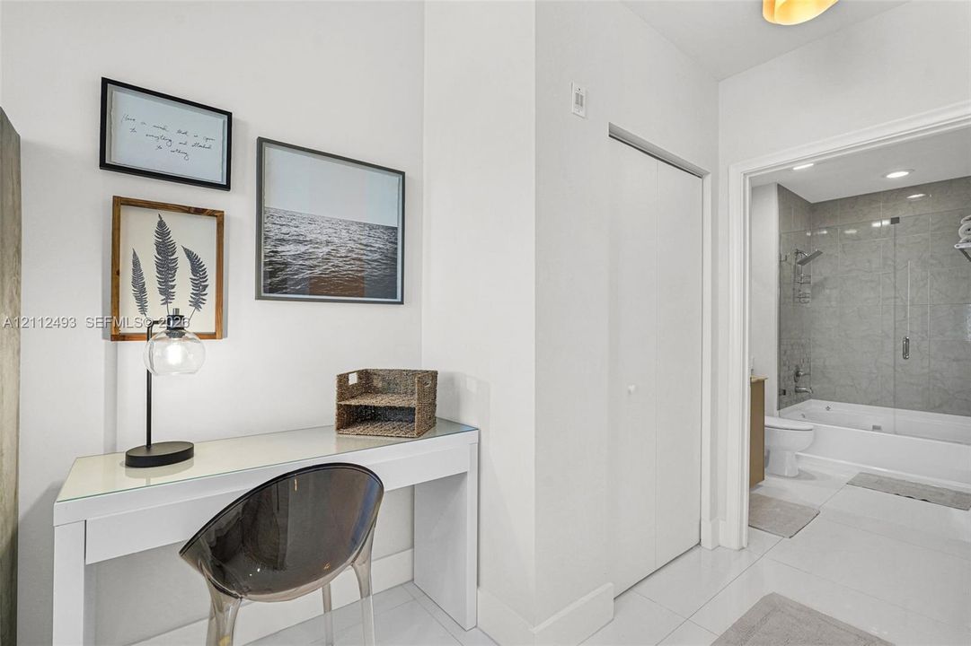 Built-in console table with a glass surface, gloss-finish closet doors, and recessed ceiling lighting