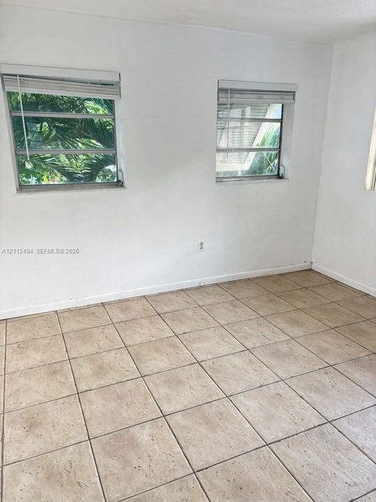 Neutral wall finishes, large-format square tile flooring, and two louvered-style windows
