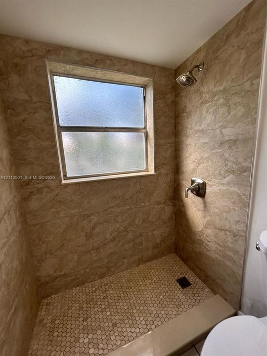 In-ground spa featuring a white border, metal handrails, and a surrounding paver patio enclosed by white fencing
