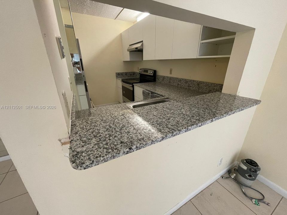 Bathroom featuring a white vanity with integrated basin, light-toned countertop, floor-to-ceiling textured tile shower surround, mosaic tile shower flooring, and large-format tile flooring