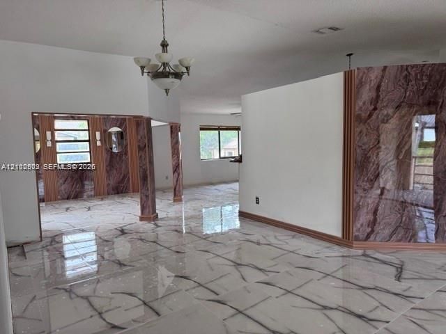 Large-format tile flooring with veined detailing, custom stone-finish accent walls, multi-light chandelier fixture, and oversized windows