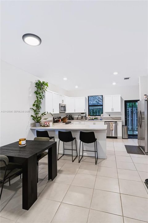 Kitchen featuring white cabinetry, solid-surface countertops, tile flooring, stainless steel appliances, and recessed lighting