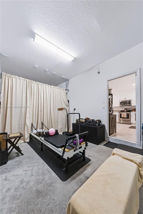 Flex space featuring concrete flooring, wall-mounted linear lighting, and a floor-to-ceiling curtain track system