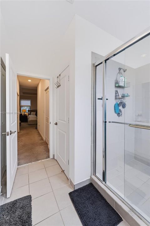 Walk-in shower featuring a glass enclosure, metal frame, and tile flooring