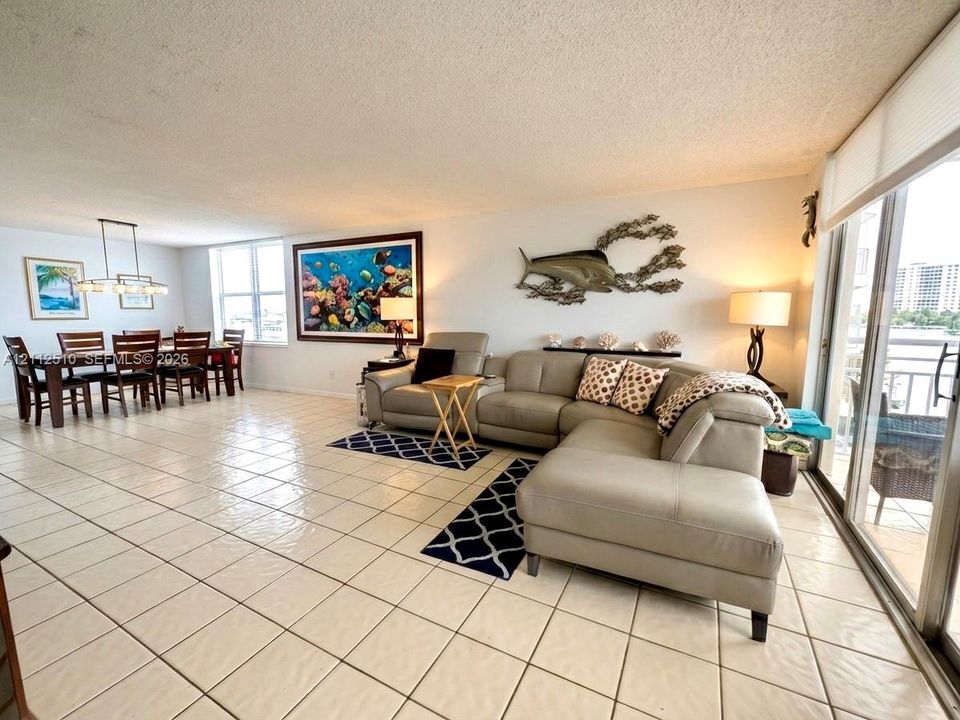 Open-concept floor plan featuring oversized ceramic tile flooring, floor-to-ceiling windows, and sliding glass doors with exterior access