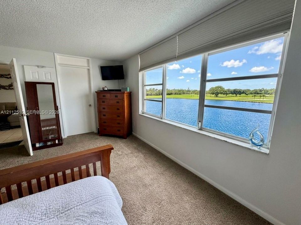 Expansive window featuring horizontal blinds, neutral wall-to-wall carpeting, and water scenery