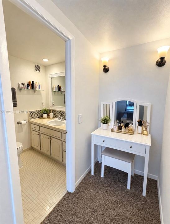 Bathroom featuring a vanity with a countertop basin, mosaic tile backsplash, framed wall mirror, and two wall-mounted light fixtures