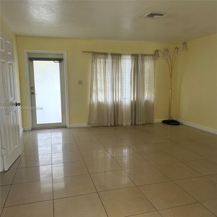 Interior space featuring large-format ceramic tile flooring, a glass-panel entry door, and a wide window configuration