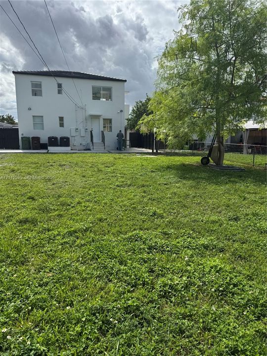 Expansive backyard featuring a grass lawn, mature tree, perimeter fencing, and a concrete patio