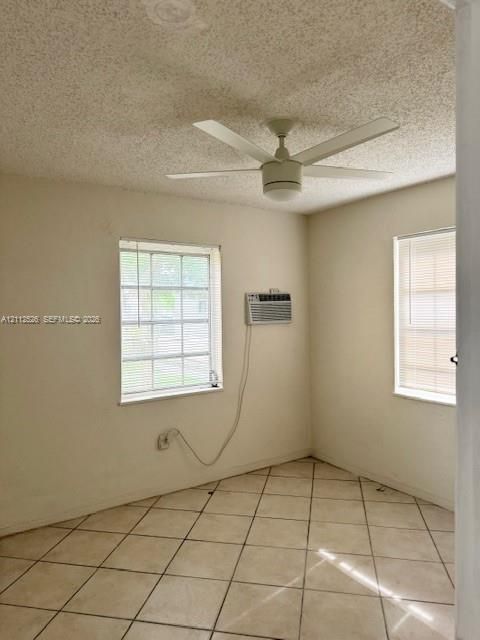 Interior space featuring neutral-toned tile flooring, multi-pane windows, and a ceiling fan with integrated lighting