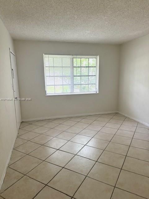 Interior room featuring large-format ceramic tile flooring, a multi-pane window with interior blinds, and a solid-core interior door