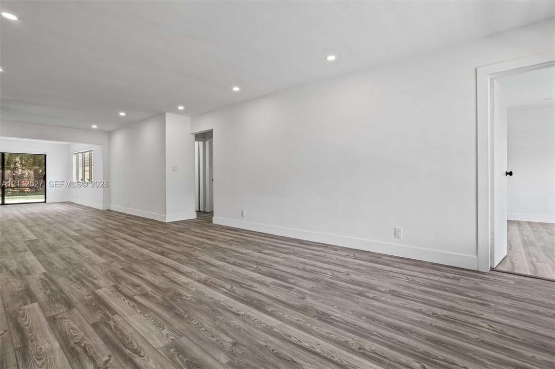 Neutral-toned interior featuring wood-finish flooring, recessed lighting, and sliding glass door access to the exterior