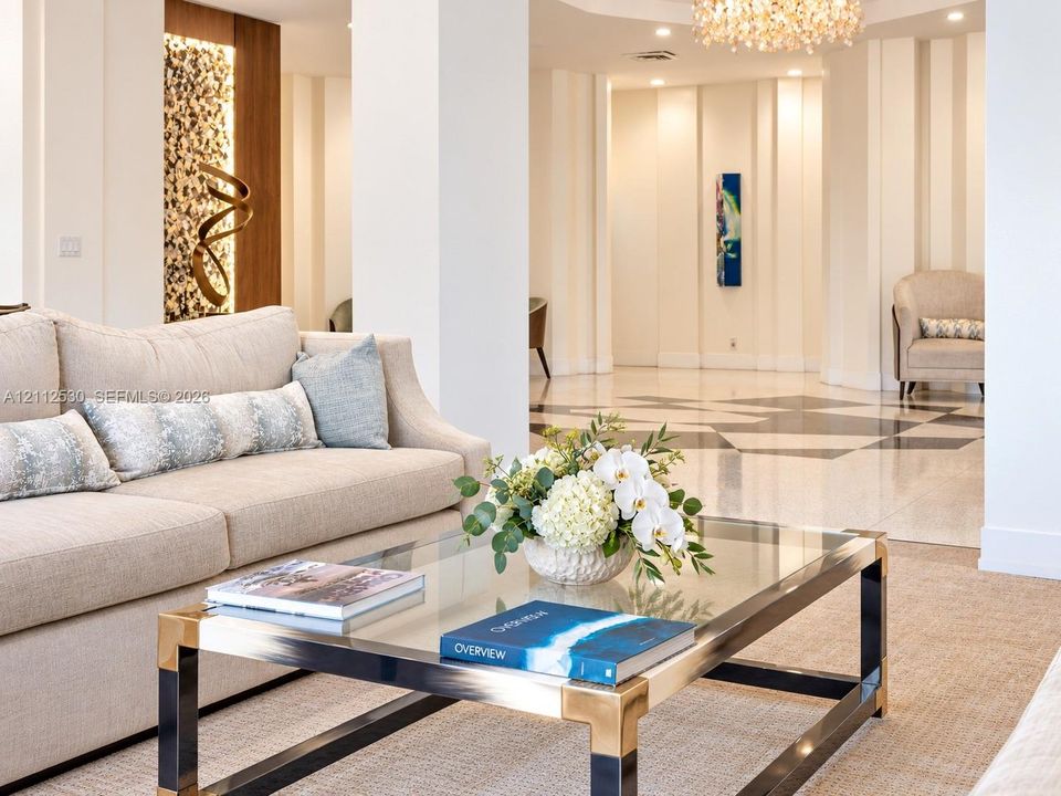 Polished stone flooring with geometric inlay, structural columns, accent wall with integrated vertical lighting, and decorative chandelier