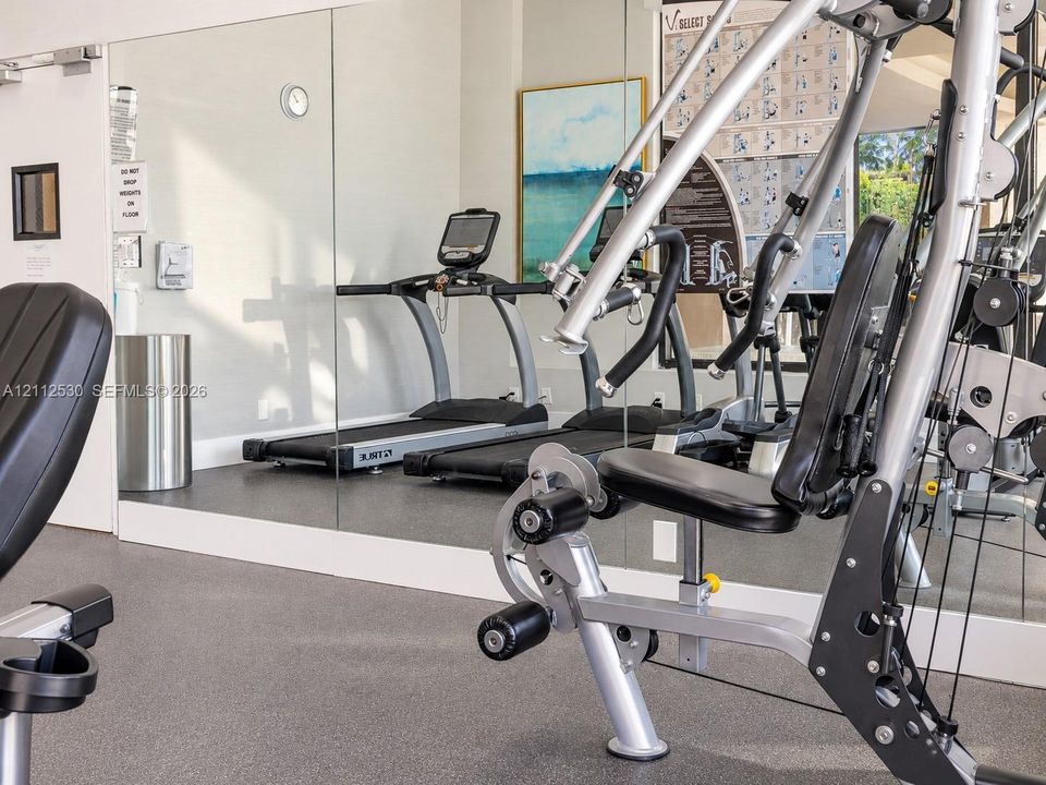 Fitness center featuring floor-to-ceiling mirrored walls and durable, high-impact rubberized flooring