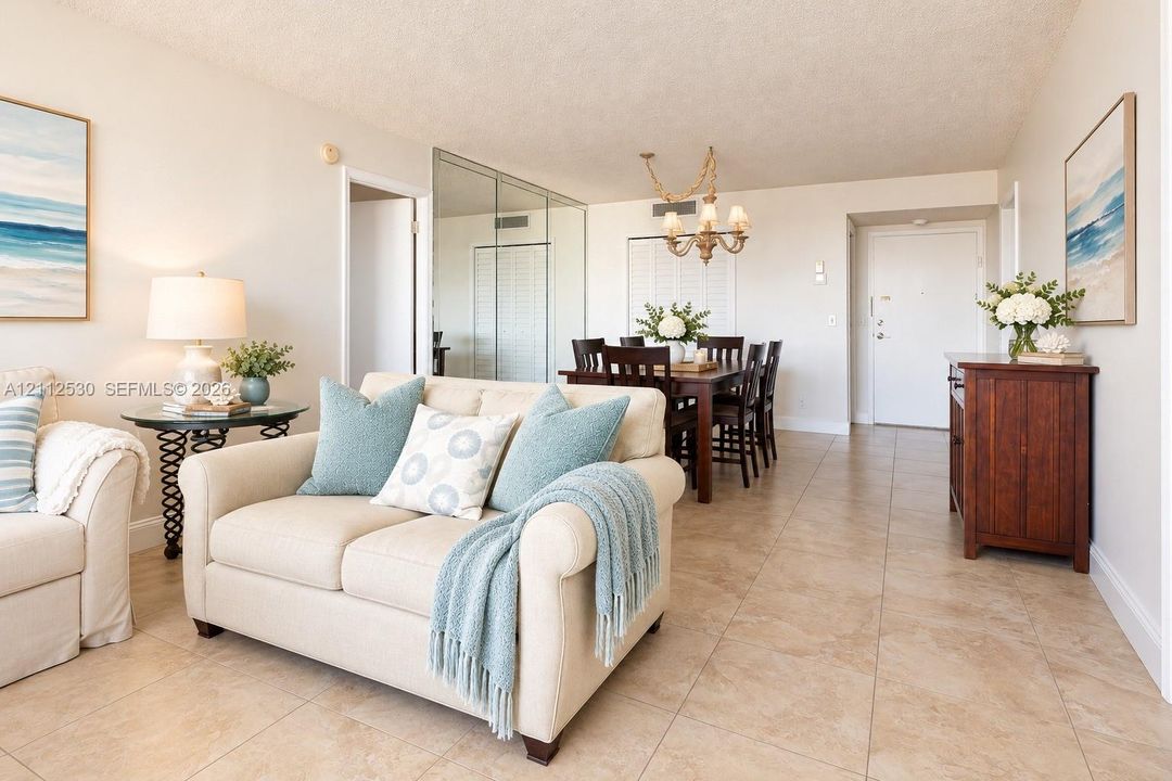 Neutral-tone tile flooring, mirrored sliding closet doors, and decorative multi-arm chandelier lighting