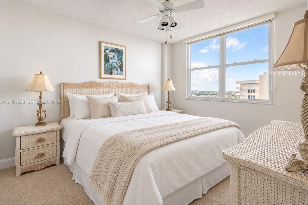 Neutral-toned carpeted flooring, large double-pane window, and a multi-bulb ceiling fan with integrated lighting