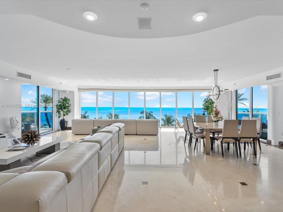 Open-concept living space featuring floor-to-ceiling windows, polished stone flooring, recessed lighting, and expansive water scenery
