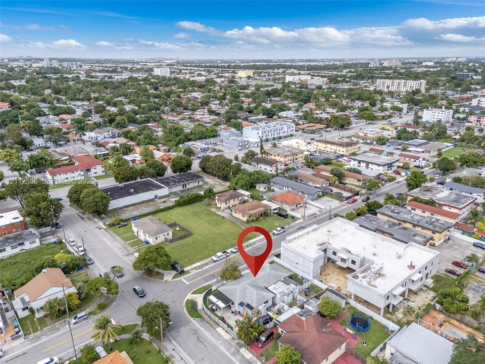 Aerial perspective of a corner lot property featuring a hip roof structure, paved driveway, and established perimeter fencing