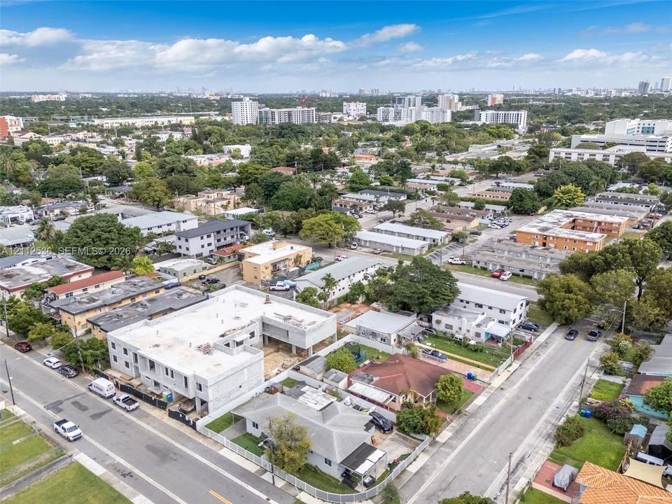 Aerial perspective of a multi-level concrete residential structure under construction featuring an open-concept building footprint and urban surroundings