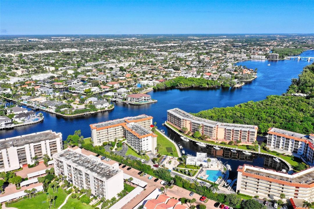 Aerial perspective of waterfront mid-rise structures featuring integrated boat slips, open-air parking, and a communal swimming pool