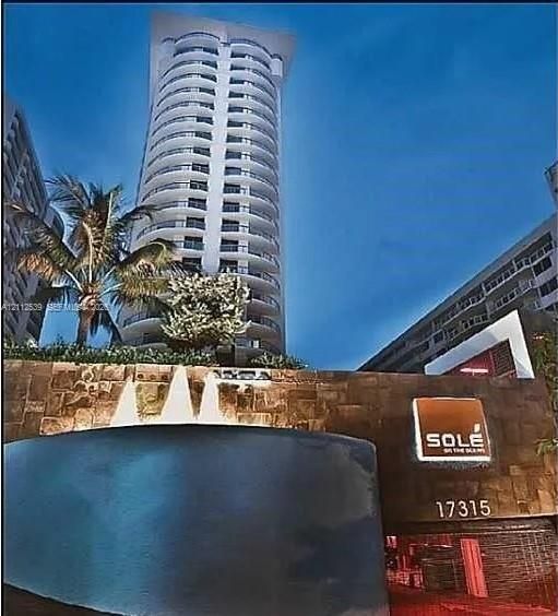 High-rise residential tower featuring curved balconies, stone-clad masonry wall, and a multi-tiered water fountain