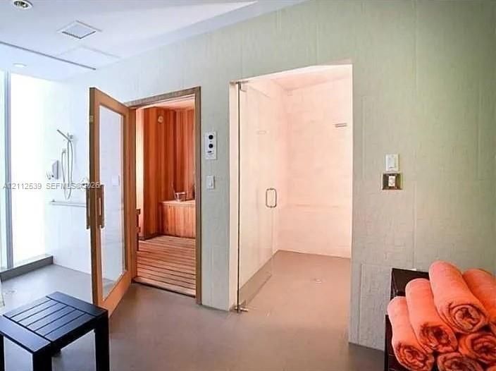 Sauna featuring cedar paneling and wood-slat flooring, accompanied by a glass-enclosed steam shower with tile surround and wall-mounted shower hardware