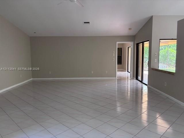 Vaulted ceilings featuring a recessed ceiling fan, neutral wall paint, and ceramic tile flooring throughout, characterized by large sliding glass doors and a wall-cutout serving window