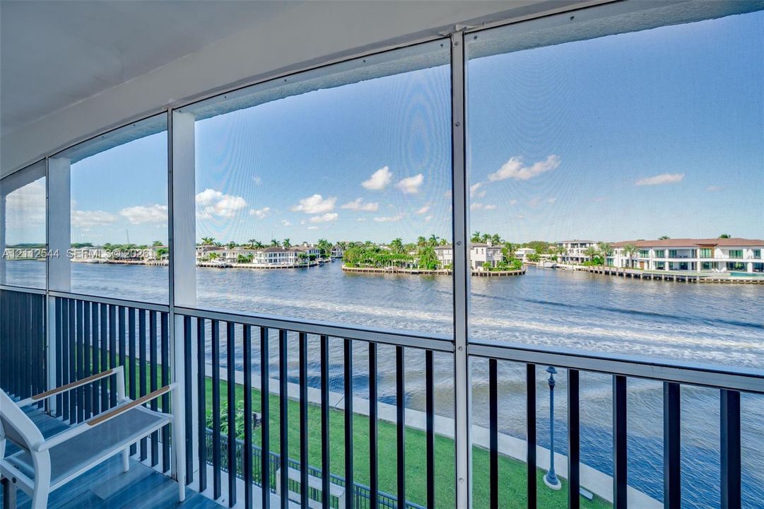 Screened-in balcony featuring black vertical railings, tile flooring, and waterfront scenery