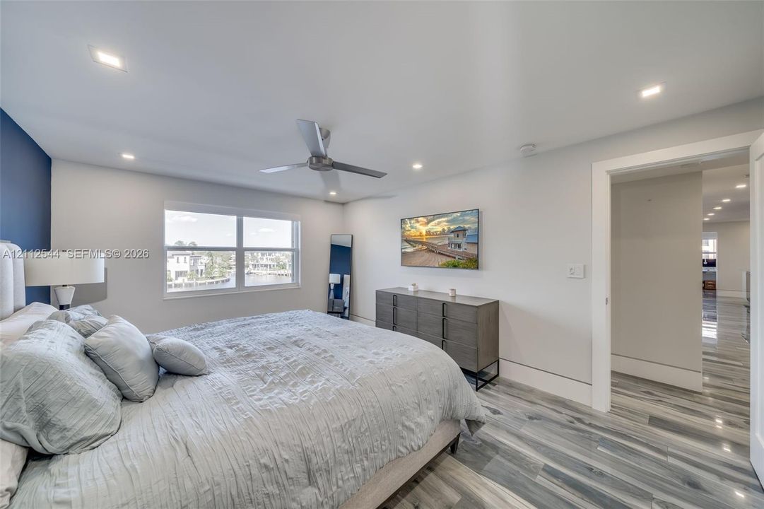Bedroom featuring multi-tonal wood-finish flooring, recessed lighting, a modern ceiling fan, and a dual-pane window