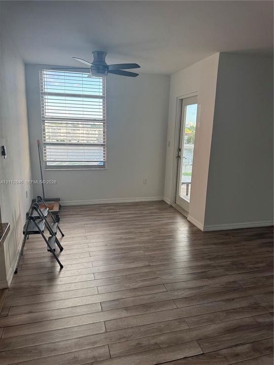 Wood-finish flooring, multi-pane window with horizontal blinds, ceiling fan, and glass-paneled exterior door