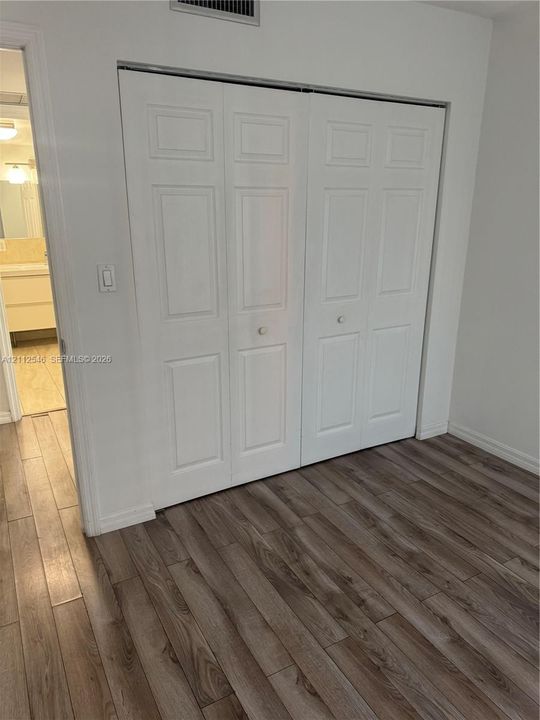 Bi-fold closet doors with white raised-panel detailing and wood-finish flooring
