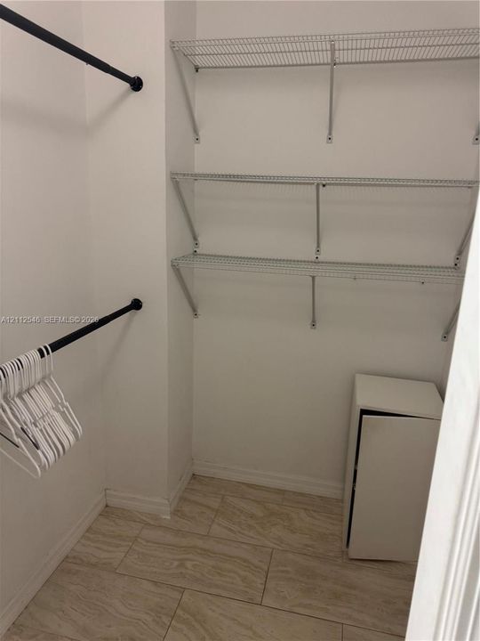 Storage area featuring tile flooring, matte black hanging rods, and multi-tier wire shelving