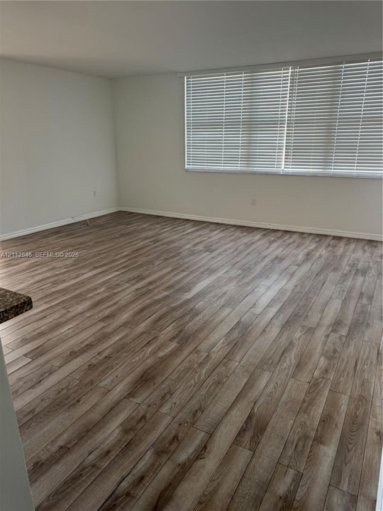 Interior room featuring wood-finish flooring, neutral wall tones, and horizontal window blinds