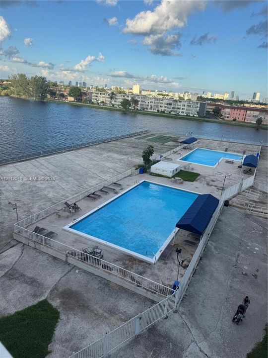 Waterfront community amenities featuring two in-ground swimming pools, concrete pool deck, and fabric shade awnings