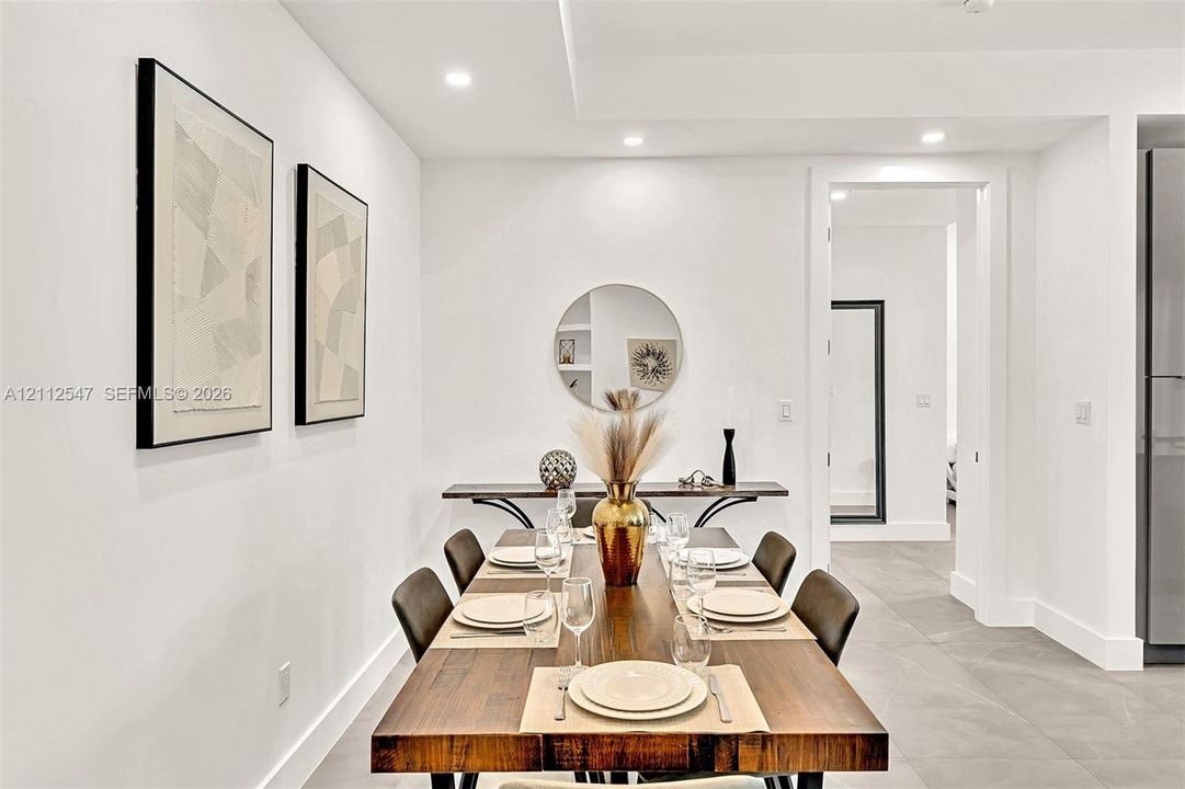 Neutral interior space featuring recessed ceiling lighting, a tray ceiling detail, tile flooring, and a built-in wall niche