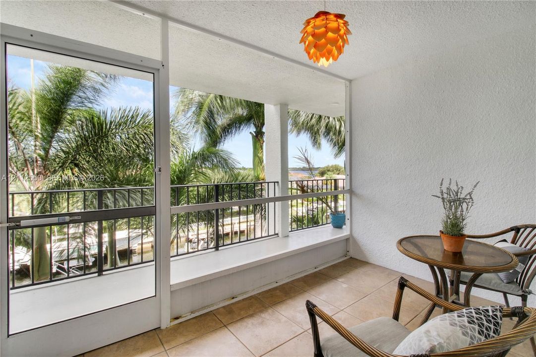 Enclosed balcony featuring tile flooring, textured wall finishes, and a metal railing