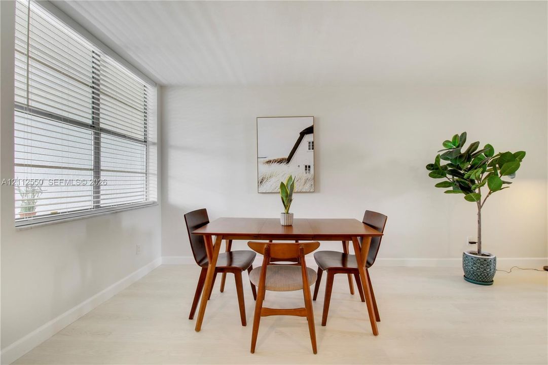 Neutral wall palette with wood-finish flooring and large-scale window featuring adjustable horizontal blinds