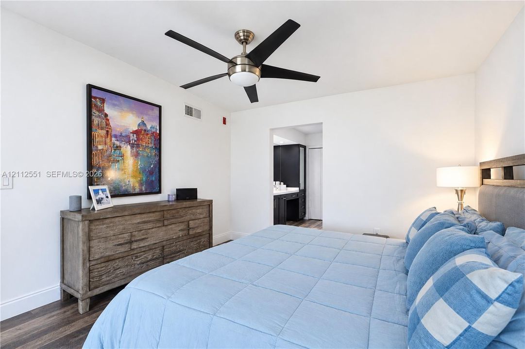 Room featuring wood-finish flooring, a matte black multi-blade ceiling fan with integrated lighting, and neutral wall color