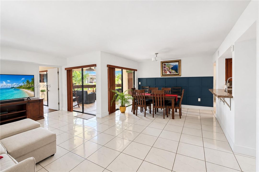 Large format ceramic tile flooring, dual sliding glass doors, and a deep-blue grid wainscoting accent wall, complemented by a kitchen pass-through counter