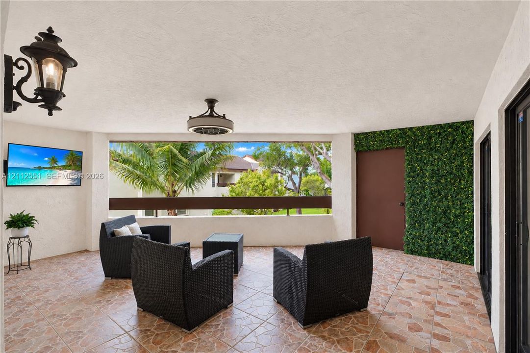 Covered patio featuring tiled flooring, built-in wall-mounted light fixture, decorative plant wall finish, and a ceiling-mounted light