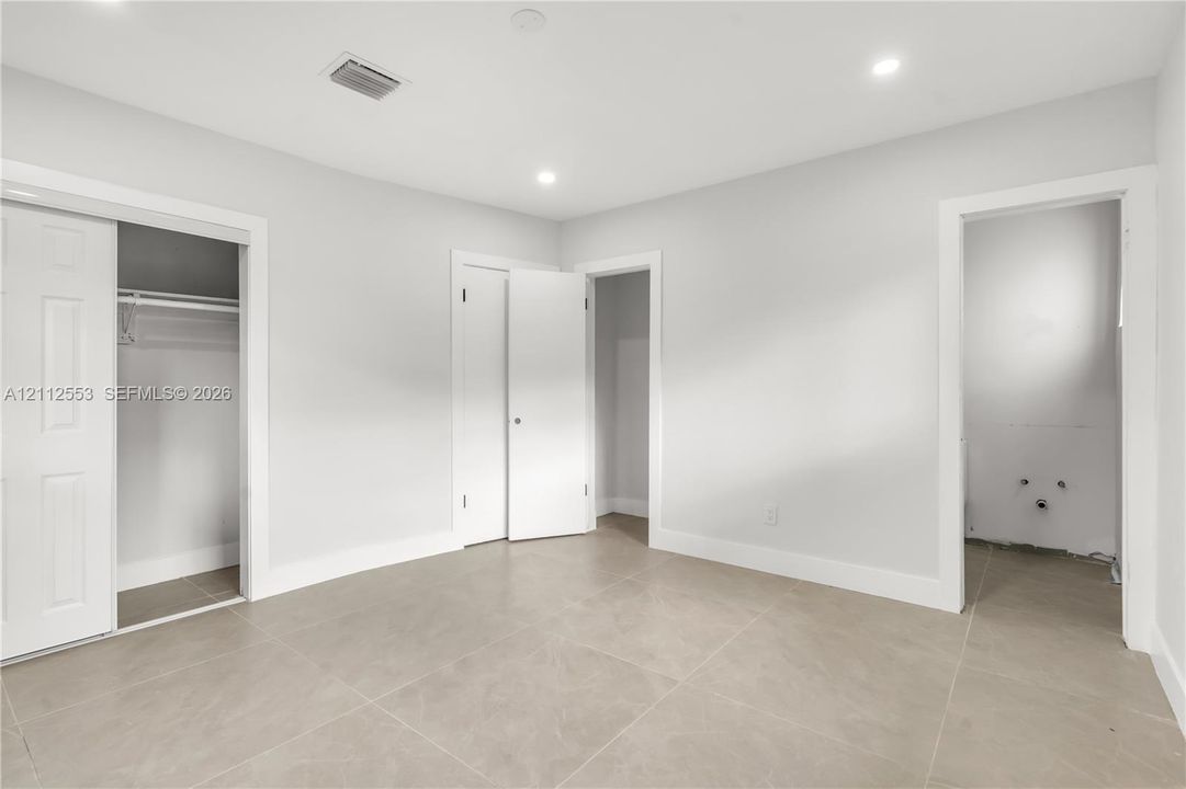 Neutral-toned ceramic tile flooring, recessed ceiling lighting, and multiple interior closets with white paneled doors