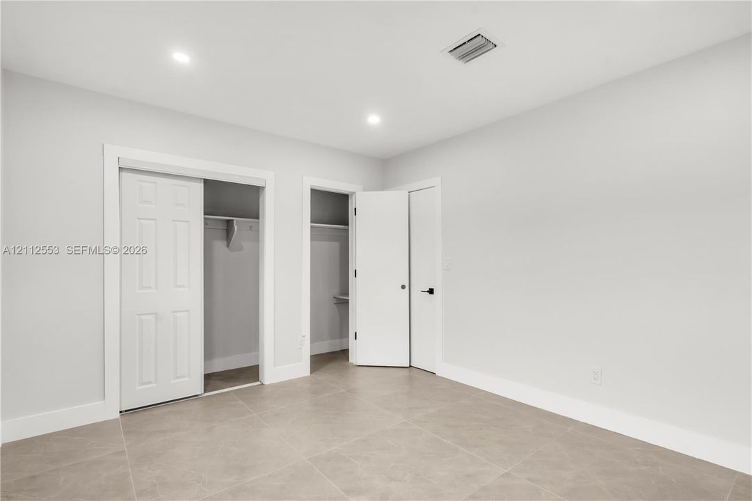 Neutral-toned tile flooring, recessed ceiling lighting, two reach-in closets, and solid-core doors with matte black hardware