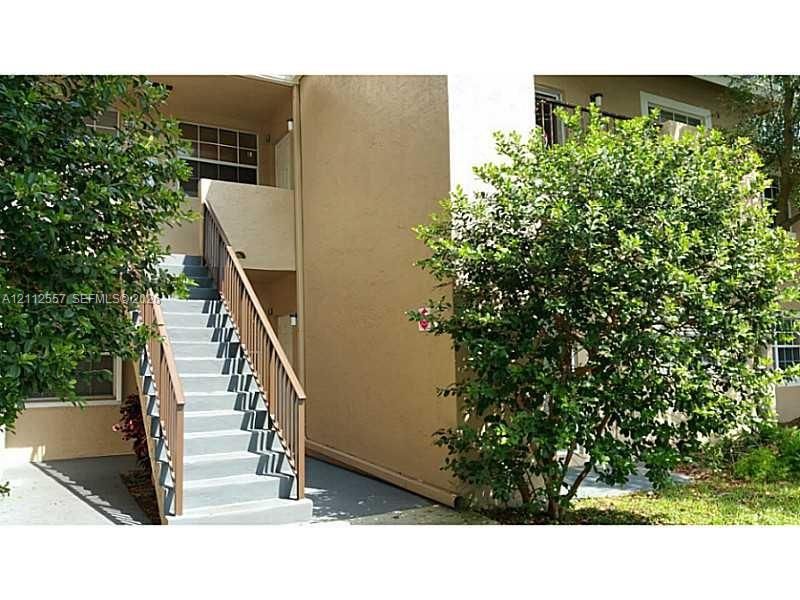 Exterior staircase with wooden railings featuring concrete steps and stucco siding