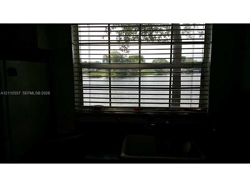 Single-basin under-mount sink, horizontal slat blinds, and exterior water frontage